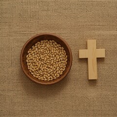 Wooden bowl filled with wheat and a wooden cross on a rough fabric surface