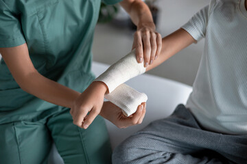 Nurse wrapping bandage around child’s injured arm
