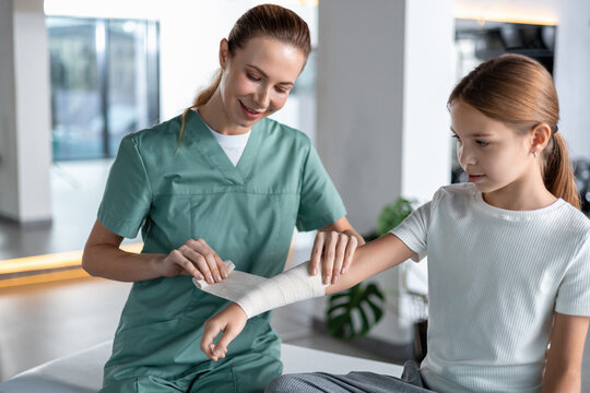 Nurse wrapping bandage around child&rsquo;s injured arm