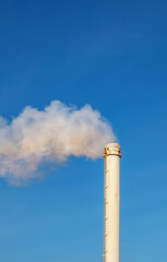 a tall, white industrial chimney releasing a plume of smoke into a clear blue sky, exhaust waste gases, known as flue gases, from various industrial processes to the outside air