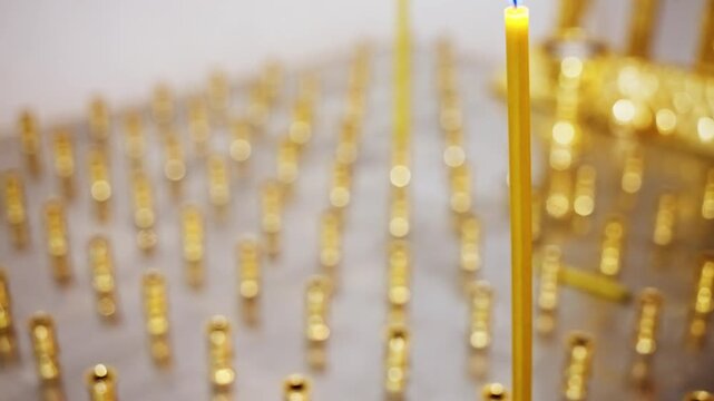 Single Tall Gold Candle Burning Amid Rows Of Empty Gold Holders On Altar, Soft Warm Glow, Shallow Depth Of Field, Reflective Metal Surface, Serene Ritual Atmosphere Evoking Devotion And Prayer