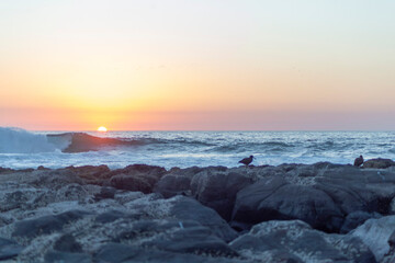 Sunset on the beach, rocks, water, sun and sky 