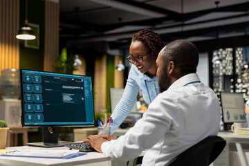 Two black workers interacting with a virtual assistant on computer at desk, AI generated responses and smart automation to improve online communication. Data driven AI solutions.