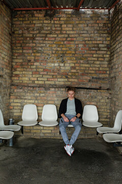 Young man waiting alone in industrial interior with brick wall