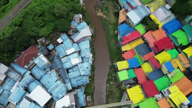 Drone view of Kampoeng Warna Warni Jodipan colorful village in Malang, East Java, Indonesia. Aerial cityscape of vibrant bright houses, Brantas river and bridge. Travel and tourism concept.