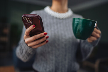 Woman holding smart phone and coffee cup enjoying break