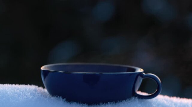 Close up of dark blue tea cup in snow with gentle movement and calm winter mood