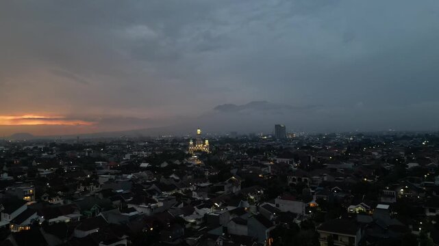 Aerial Drone View of Malang Cityscape, East Java, Indonesia, Featuring Traditional Red Roof Houses, Urban Landscape, and Misty Volcano Mountains in the Background at Sunrise