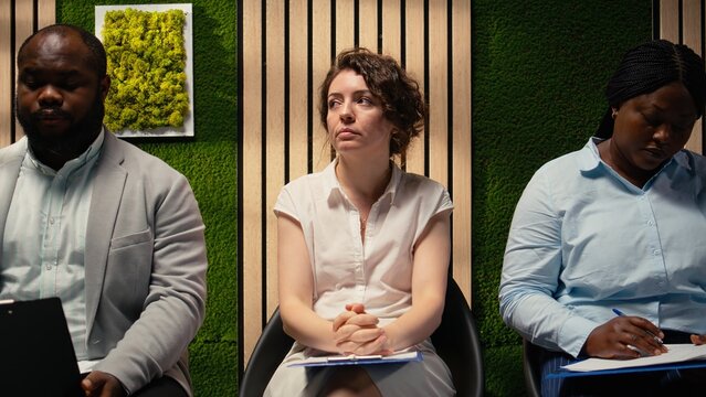 Scared impatient woman applicant getting extremely nervous and agitated while she waits in the queue outside HR office. Person sitting in line under pressure, deals with anxiety. Camera A.