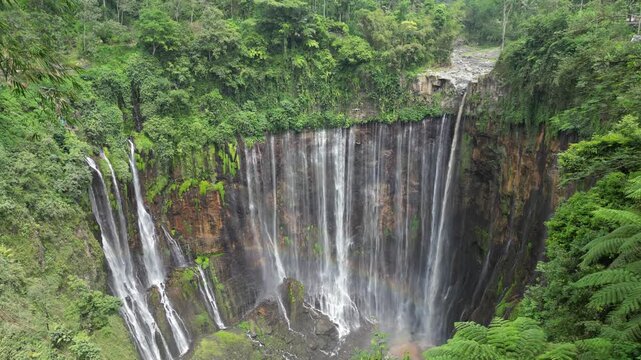 Drone aerial view of Tumpak Sewu Waterfall, East Java, Indonesia. Spectacular dramatic canyon, lush tropical rainforest jungle and majestic volcanic landscape scenery. Famous tourist travel destinatio