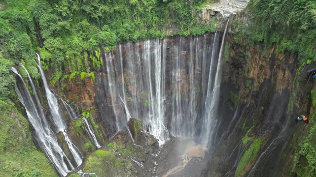 Drone aerial view of Tumpak Sewu Waterfall, East Java, Indonesia. Spectacular dramatic canyon, lush tropical rainforest jungle and majestic volcanic landscape scenery. Famous tourist travel destinatio