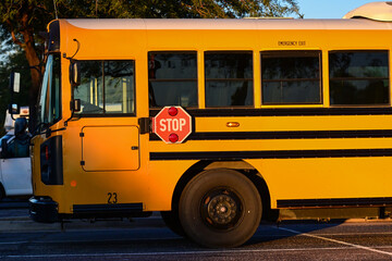 Yellow school bus with extended stop sign driving on a roadway, representing student transportation services, road safety procedures, and public school transit operations