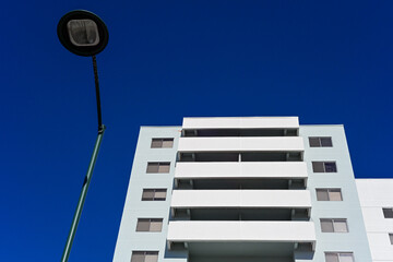 Streetlight in foreground with modern high rise residential building in background, representing urban infrastructure, public lighting, and multifamily housing development