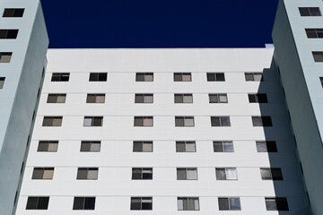 Modern multifamily residential building with window pattern against a clear sky, representing urban housing development, large scale apartment construction, and contemporary real estate architecture