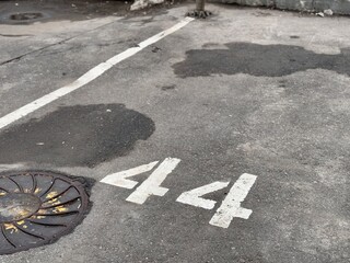 Urban Parking Detail, Faded Parking Spot On Rough Pavement, Weathered Parking Space Amid Gritty Urban Environment, Silent City Lot Showcasing Worn Markings And Textured Surface Details