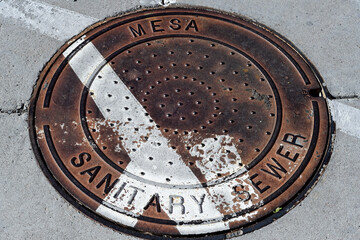 Close view of a sanitary sewer manhole cover on pavement, representing municipal wastewater infrastructure, underground utility access, and public works maintenance