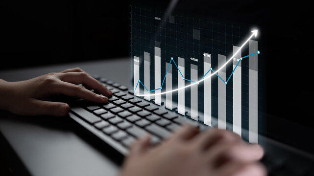 A close-up image of hands typing on a keyboard, featuring a digital graph overlay that symbolizes business growth and financial analysis in a modern workspace. Impute - Powered by Adobe