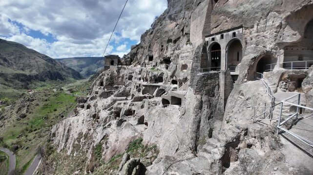Vardzia, a 12th-century cave monastery carved into Erusheti cliffs, displays ancient architecture against a cloudy sky, reflecting medieval ingenuity and religious heritage