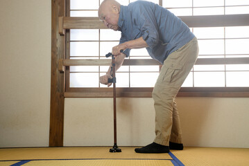 杖を使用して室内でリハビリをしている老人