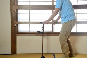 杖を使用して室内でリハビリをしている老人