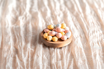 wooden bowl filled with mini eggs on a beige background.