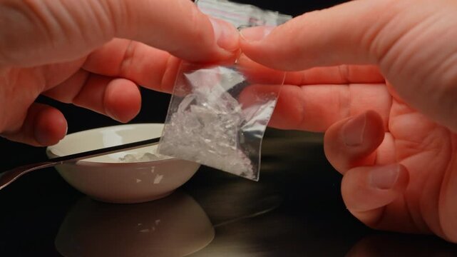 Drug dealer packaging crystal drug in clear plastic bags for distribution concept. Fentanyl crisis, illegal drugs Cocaine, Crystal meth or Crack Cocaine.