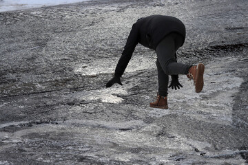 Rutschgefahr auf einem glatten Gehweg im Winter. Eine Frau ist auf dem Eis ausgerutscht.