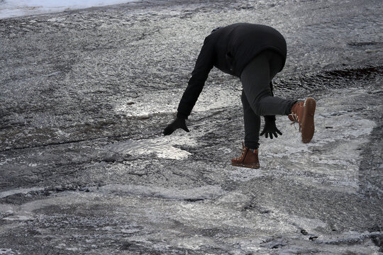Rutschgefahr auf einem glatten Gehweg im Winter. Eine Frau ist auf dem Eis ausgerutscht.