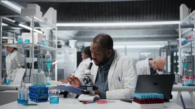Lab researcher looking through scientific microscope lens to study cells. African american man performing biological sample examination with high tech optical equipment, camera A