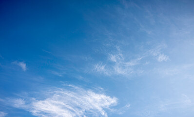 wide-angle view of a vibrant blue sky featuring delicate, wispy white clouds. This high-resolution image captures a bright, sunny day, perfect for nature backgrounds and airy designs.