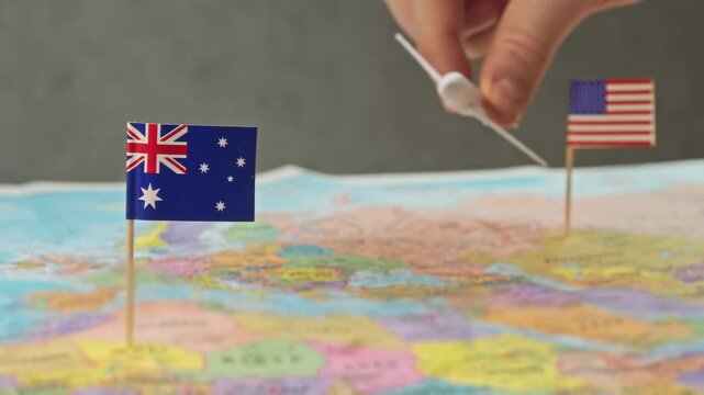 Toy airplane near United States and Australia flags on political world map, symbol transpacific carriers, route network growth and strategic partnership in Australia international air transport.