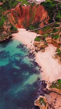 Aerial rise shot of Praia do Camilo Beach and Cliffs in Lagos, Algarve, Portugal Vertical video 