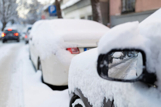 Snow covering parked cars along street in winter