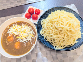 チーズをトッピングした濃厚なカレーつけ麺とミニトマト