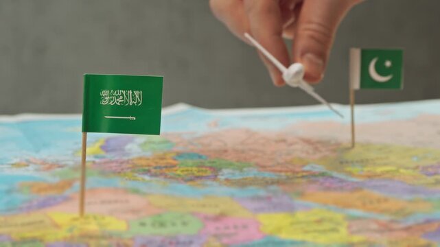 Toy airplane flying from Pakistan to Saudi Arabia above colorful world map, symbol Hajj routes, expatriate workers, regional airlines and intensive Gulf air traffic.