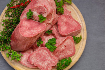Gourmet slices of boiled veal tongue served on a wooden plate