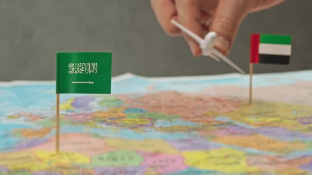 Toy airplane flying from United Arab Emirates to Saudi Arabia over colorful map, symbol business shuttles, religious tourism, regional carriers and dense Gulf air network.