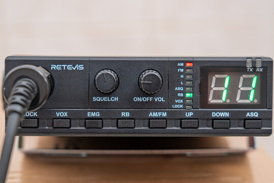 CB car radio, 27MHz citizen band, 40 channels, RETEVIS brand, with PTT, female connector and 12-volt cigarette lighter plug. Black, rectangular shape with green LED channel indicator.
