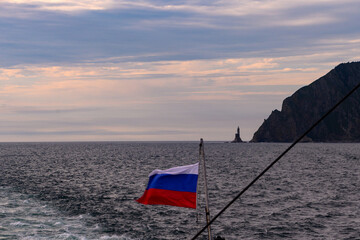 Waves and winds capture the beauty of a lighthouse under a cloudy sky near Russia's coastline
