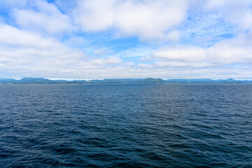 Calm waters reflect a serene sky over distant mountains in the early morning