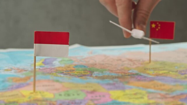 Toy airplane between China and Indonesia flags over colorful world map, symbol transfer traffic, group tourism, low cost carriers and growing role of Indonesia in China ASEAN air routes.
