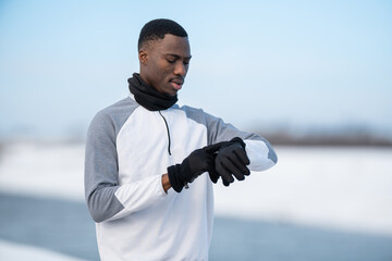 Man checking fitness tracker during winter running workout