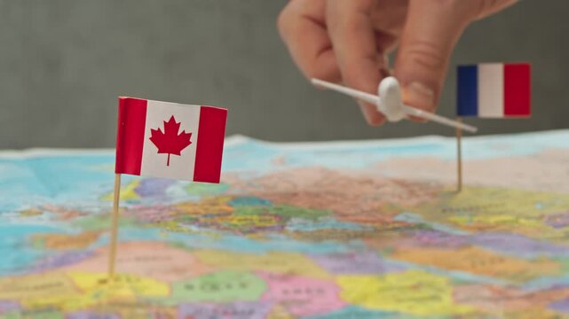 Toy airplane near France and Canada flags over colorful world map, symbol Paris Montreal corridor, long haul routes, tourism and business travel demand in Canada.