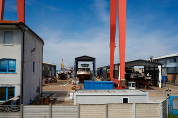Large yacht being lifted by crane in a shipyard.