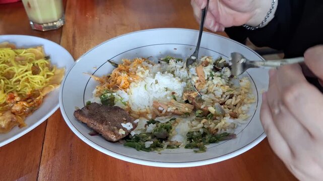 Enjoying mixed rice dish with beef jerky and green chili pepper sauce and bean sprouts topped with spiced grated coconut
