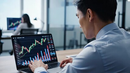 Focused Asian businessman analyzing stock market data on a laptop in a modern office for financial investment concept and digital trading strategy - Powered by Adobe