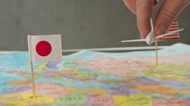 Toy airplane between United States and Japan flags above detailed world map, symbol premium carriers, alliance networks, tourism charters and strategic US presence in Japan aviation market.
