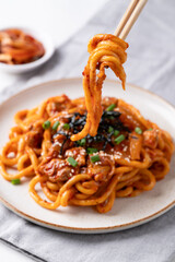 Stir fried Udon noodle with kimchi cabbage, pork, spring onion, sesame seed and seaweed eating by chopsticks