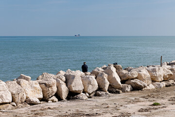 Rear view of senior retired man sitting at seaside