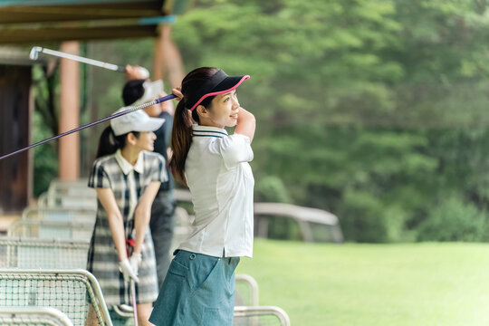 Golf player practicing swing at golf driving range, driving range, golf center, female golfer